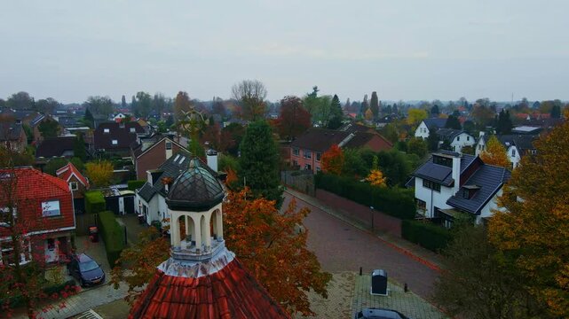 Aerial view of a decorated crucifix on top of a small town overlooking a quiet suburban neighborhood in the Netherlands on an overcast autumn day