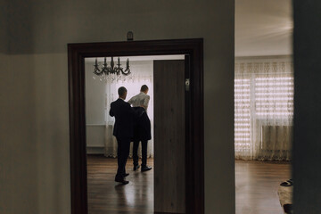 Fototapeta premium A man in a suit is standing in front of a door with two other men standing behind him