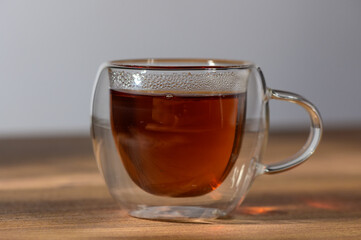 Warm cup of herbal tea resting on wooden table, illuminated by soft morning light in a cozy kitchen setting