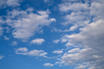 Obraz premium Fluffy white clouds drift across a vibrant blue sky on a serene afternoon in early spring