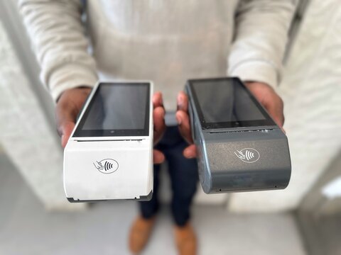 Closeup a man holding payment machine or card reader. E-money at cashless wallet of client. EDC Machine or Credit card terminal. Smartphone Mobile payment Concept.