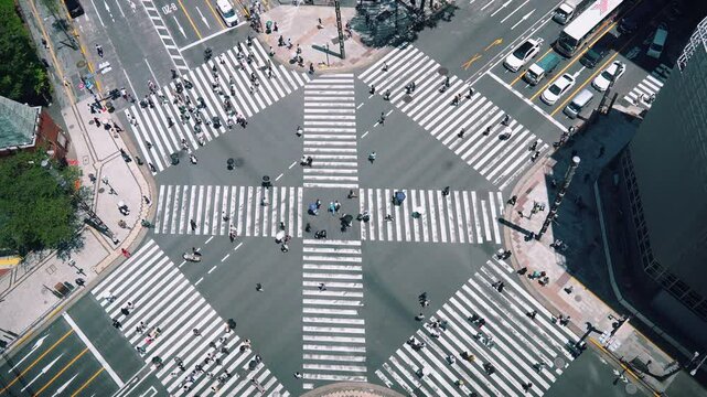 Slow-motion top view of Ginza crossing in Tokyo, Japan. Crowds of people flow through this iconic intersection, highlighting the dynamic energy of bustling city life.