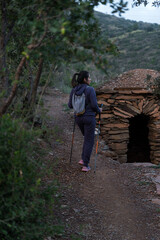 A woman stops to contemplate the natural landscape next to a mountain shelter.