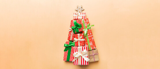 Christmas tree made of beautifuly wrapped presents on colored background, view from above. New Year gift box minimal concept with copy space