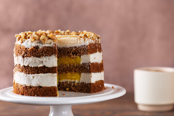 Pumpkin spice or carrot layered cake with vegan cream and orange confit decorated with walnut and cup of coffee. Homemade cake, sugar, gluten and lactose free.