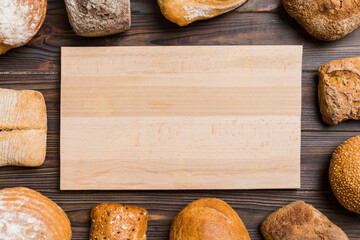 Minimalist wooden cutting board blank mockup on background of Types of homemade bread. Different...