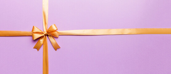 Top view of gold ribbon rolled and yellow bow isolated on colored background. Flat lay with copy space