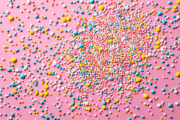 Colorful sprinkles on a pink background, top view with copy space