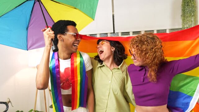 Multi-ethnic friends waving lgbt rainbow flag and dancing partying at home and celebrating pride together