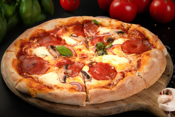 Homemade pepperoni pizza with basil on black background	