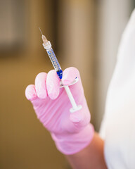 Syringe in the doctors hand with filler - subcutaneous injections of hyaluronic acid in the salon of aesthetic medicine - rejuvenation and smooth skin