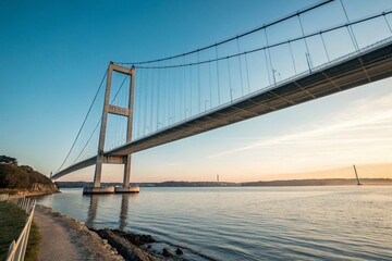 Minimalist View of an Architectural Suspension Bridge Against a Clear Sky, Showcasing Its Elegant Lines and Structure with a Calm Reflection on the Water Below