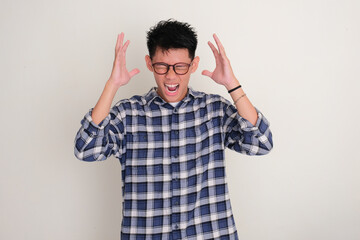 Young Asian man screaming crazy showing frustration