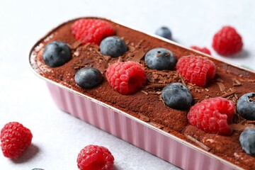 Delicious tiramisu cake with berries on table