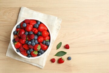 Different fresh ripe berries in bowl on the table, top view