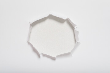 Center torn hole in white paper revealing a white glitter texture background. Space for text.