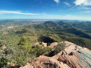 Wide panoramic image capturing a scenic view of green, forested hills from a natural park lookout point. Clear skies and distant landscapes enhance the sense of vastness and tranquility.