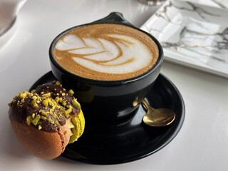 Cup of coffee lattee with macaroon on a plate 