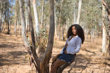 Latin woman, young, beautiful, brunette, with curly hair, with a white shirt, top and boots, denim...