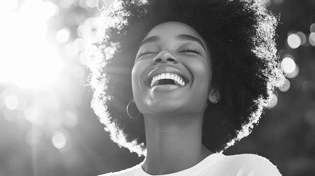 A joyful woman with an afro smiles brilliantly, illuminated by natural sunlight, capturing a moment of happiness and vitality.