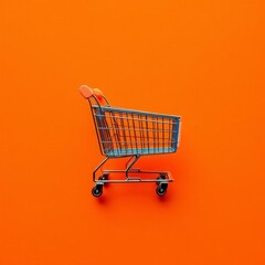 Metal supermarket shopping cart over vivid yellow / orange background