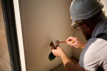 Builder installing electric socket in new apartment. Installing electrical wall outlets with a...
