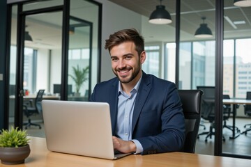 Fototapeta premium Professional Man in Office Setting Working on Laptop Smiling Confidently in Modern Workspace