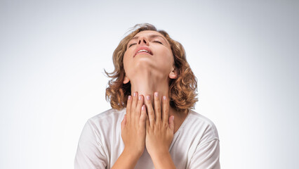 High-quality image of a woman holding her throat in pain, head tilted back against a plain background. Perfect for articles and advertisements related to throat pain, health issues, and medical care.