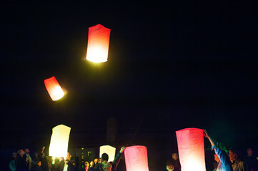 A vibrant display of red and yellow lanterns gliding silently through the dark sky, creating an enchanting and serene atmosphere during a nighttime festival or celebration.