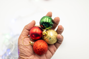 Feel the warmth of the holiday season with this close-up image of a hand gently holding colorful Christmas ornaments.  