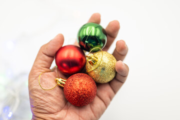 Feel the warmth of the holiday season with this close-up image of a hand gently holding colorful Christmas ornaments.  