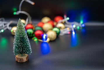 Embrace the festive spirit with this charming Christmas image featuring miniature Christmas trees nestled amongst colorful ornaments and sparkling fairy lights.