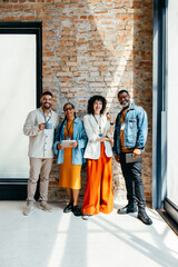 Stylish group of professionals standing cheerfully with tablets and coffee