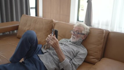 Senior man is playing smart phone in living room. Leisure activity, technology.