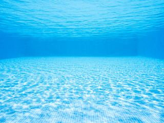 background of underwater view of a blue swimming pool with glowing water with ripples above tiled bottom on sunny day, concept of summer, copyspace for text