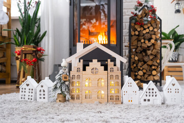 Key on Christmas tree and tiny house on cozy home with Christmas decor near the burning stove fireplace. Gift for New Year. Insurance, moving to new house, mortgage, rent and real estate