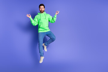Fototapeta premium Full size photo of pretty young male jumping meditate wear trendy green outfit isolated on purple color background