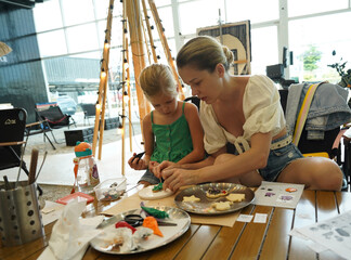 Mother and her daughter paint Halloween cookies 