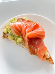 A delicious slice of avocado toast topped with smoked salmon perfect for brunch or a healthy snack.