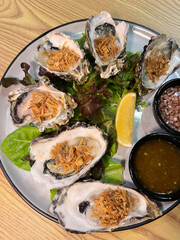Savor a fresh oyster platter featuring succulent seafood served with flavorful dipping sauces and garnishes.