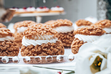 Close-up of elegant cream-filled choux pastries with a golden, crunchy topping. The rich texture and intricate design make them a perfect addition to a refined dessert table.