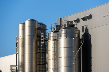 Industrial silos gleaming under blue sky, modern food processing plant