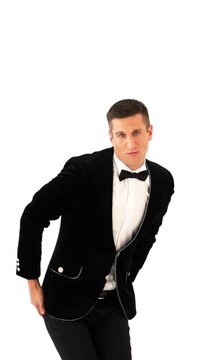 funny man in a black suit and white shirt is dancing macarena on the background of white studio. Parody of the popular dance. Macarena Vertical video
