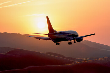 Fototapeta premium 夕焼けの空から太陽、山間部の空を飛ぶ飛行機