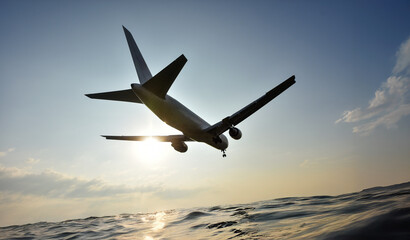 夕焼けの空から太陽が差し込む、海の上を飛ぶ飛行機