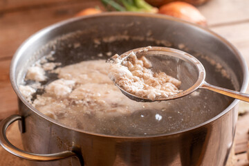 Foam from cooking chicken. Boiling water in a pan. Bone broth