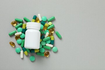 Various pills and medicine bottle, top view on gray background