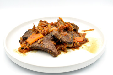 Fried pork liver with carrots lies on a white plate.