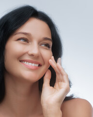 Close-up of a smiling woman with dark hair and clear skin, radiating natural beauty against a...