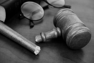 Fototapeta premium Close up of broken judge gavel, eyeglasses and legal book. Injustice and problems in legal system concept.